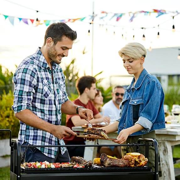 Two adults standing over a large BBQ