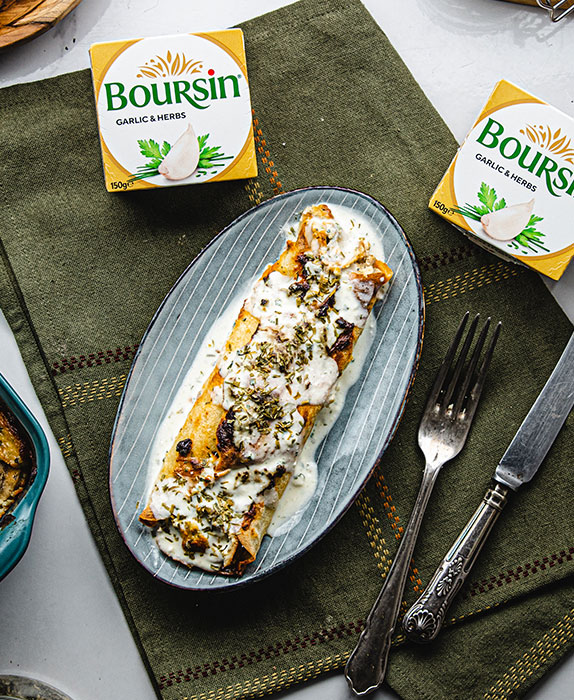 Two packs of Boursin Garlic & Herbs on a folded green table cloth